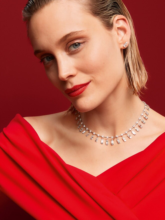 Una mujer de perlo rubio con un vestido rojo mira a la cámara mientras luce una cadena Wempe x ASHOKA®