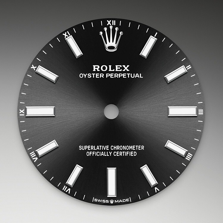 Der Radialschliff lässt zarte Lichtreflexe auf vielen Zifferblättern der Oyster Perpetual Kollektion entstehen. Er umfasst virtuose Bürsttechniken, mit denen Riffelungen erzeugt werden, die von der Mitte des Zifferblatts her ausstrahlen. Licht fließt an jeder Einkerbung entlang und schafft damit einen charakteristischen subtilen Schimmer, der sich mit der Bewegung des Handgelenks verändert. Sobald der Radialschliff abgeschlossen ist, wird die Farbe anhand des PVD-Verfahrens ( Physical Vapour Deposition , physikalische Gasphasenabscheidung) oder der Galvanoplastik auf das Zifferblatt aufgetragen. Eine dezente Lackierung verleiht dem Zifferblatt sein vollständiges Erscheinungsbild.
