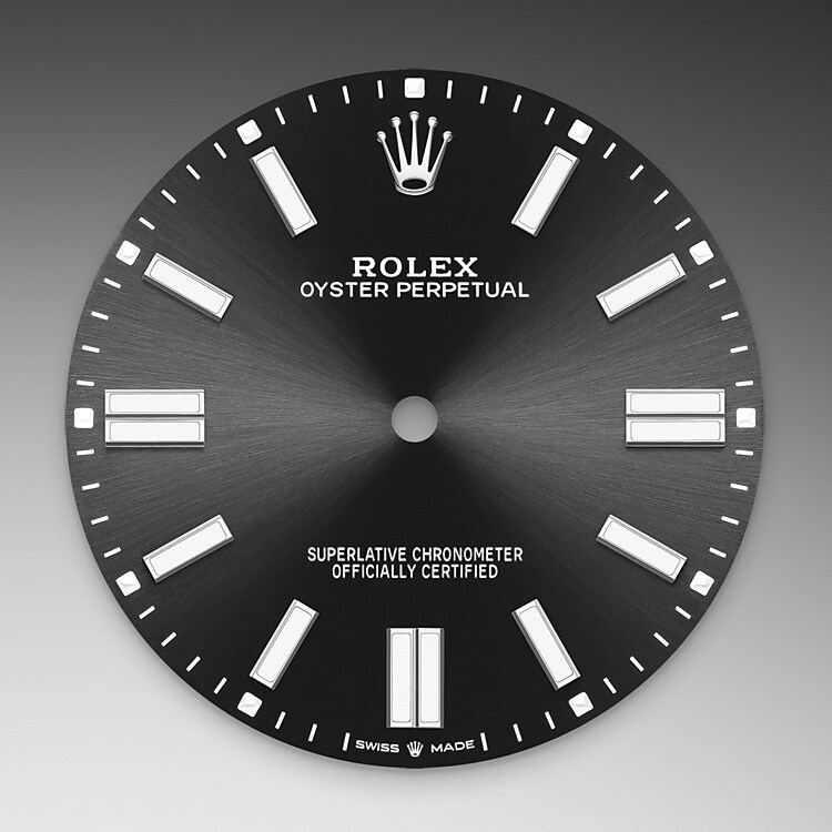 Der Radialschliff lässt zarte Lichtreflexe auf vielen Zifferblättern der Oyster Perpetual Kollektion entstehen. Er umfasst virtuose Bürsttechniken, mit denen Riffelungen erzeugt werden, die von der Mitte des Zifferblatts her ausstrahlen. Licht fließt an jeder Einkerbung entlang und schafft damit einen charakteristischen subtilen Schimmer, der sich mit der Bewegung des Handgelenks verändert. Sobald der Radialschliff abgeschlossen ist, wird die Farbe anhand des PVD-Verfahrens ( Physical Vapour Deposition , physikalische Gasphasenabscheidung) oder der Galvanoplastik auf das Zifferblatt aufgetragen. Eine dezente Lackierung verleiht dem Zifferblatt sein vollständiges Erscheinungsbild.