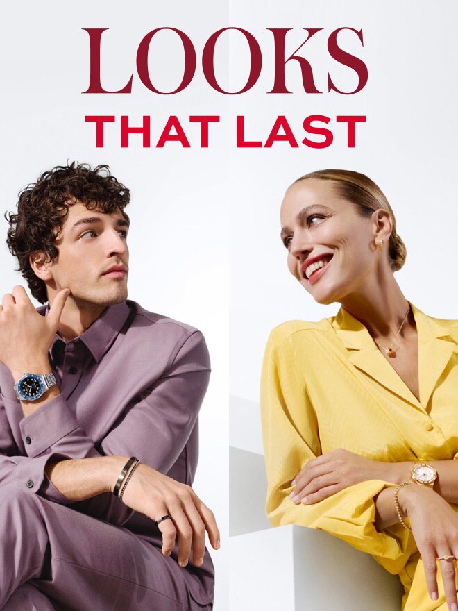 Un homme portant une tenue de couleur lilas et une femme portant une tenue jaune pastel sont assis de manière décontractée devant un fond blanc. Elle porte les bagues Basics et Everloving Renaissance by Wempe Classics serties de diamants jaunes, lui la montre Longines Spirit Zulu Time - Wempe Edition.