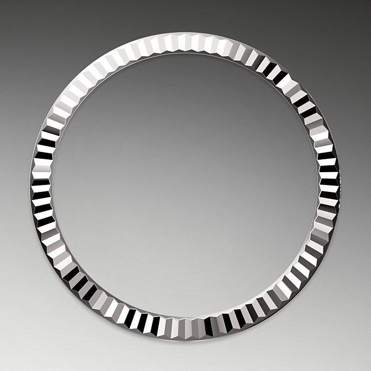 Die geriffelte Lünette von Rolex ist ein Markenzeichen. Ursprünglich hatte die Riffelung der Oyster Lünette einen praktischen Zweck: Sie diente zum Verschrauben mit dem Gehäuse, um die Wasserdichtheit der Armbanduhr zu gewährleisten. Die Riffelung entsprach deshalb der des Gehäusebodens, der ebenfalls mithilfe von Rolex Spezialwerkzeugen mit dem Gehäuse verschraubt wurde, um die Uhr wasserdicht zu machen. Mit der Zeit erhielt die Riffelung eine rein ästhetische Funktion und wurde zu einem prägenden Element des stilistischen Markenerbes von Rolex. Heute ist die geriffelte Lünette ein Distinktionsmerkmal, das bei dieser Datejust 31 in Gold gefertigt wird.