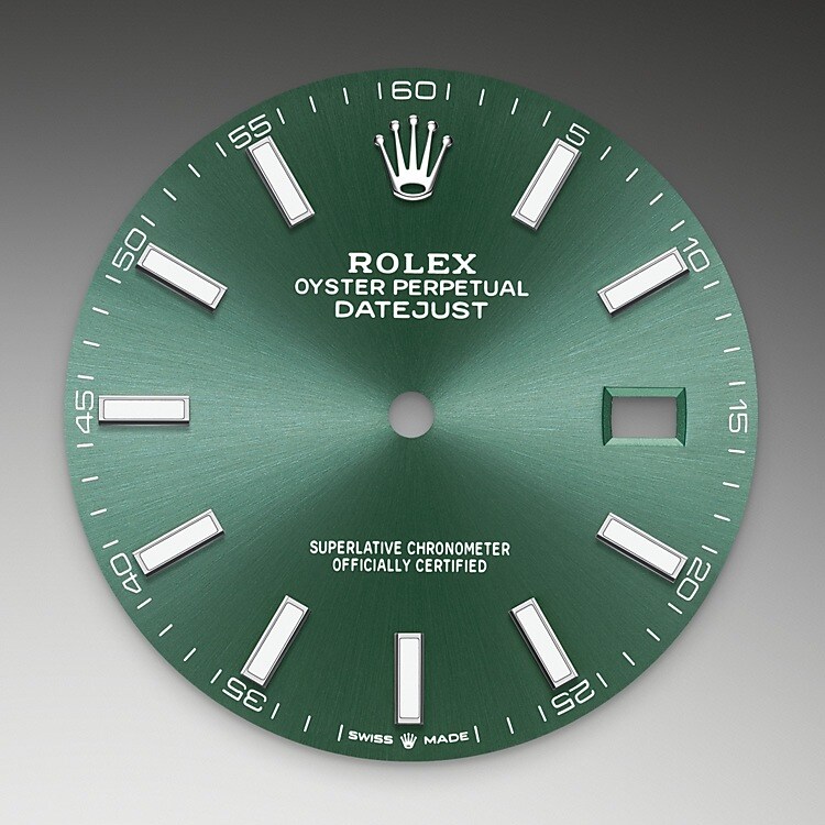 Der Radialschliff lässt zarte Lichtreflexe auf vielen Zifferblättern der Oyster Perpetual Kollektion entstehen. Er umfasst virtuose Bürsttechniken, mit denen Riffelungen erzeugt werden, die von der Mitte des Zifferblatts her ausstrahlen. Licht fließt an jeder Einkerbung entlang und schafft damit einen charakteristischen subtilen Schimmer, der sich mit der Bewegung des Handgelenks verändert. Sobald der Radialschliff abgeschlossen ist, wird die Farbe anhand des PVD-Verfahrens (<i>Physical Vapour Deposition</i>, physikalische Gasphasenabscheidung) oder der Galvanoplastik auf das Zifferblatt aufgetragen. Eine dezente Lackierung verleiht dem Zifferblatt sein vollständiges Erscheinungsbild.