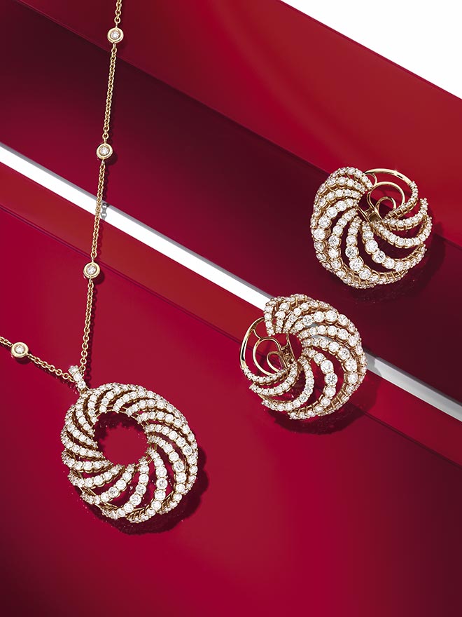 Pendants and earrings from the Spotlight line on different red surfaces
