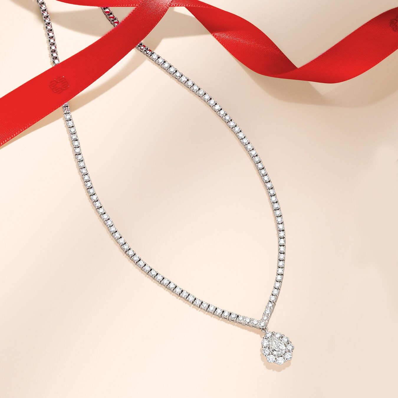 The Opulence by Wempe Statements diamond necklace on a beige background with a red ribbon The Opulence by Wempe Statements diamond necklace on a beige background with a red ribbon