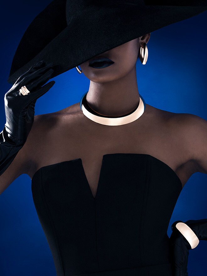 Frau mit schwarzen Handschuhen vor blauem Hintergrund trägt Schmuck von IsabelleFa