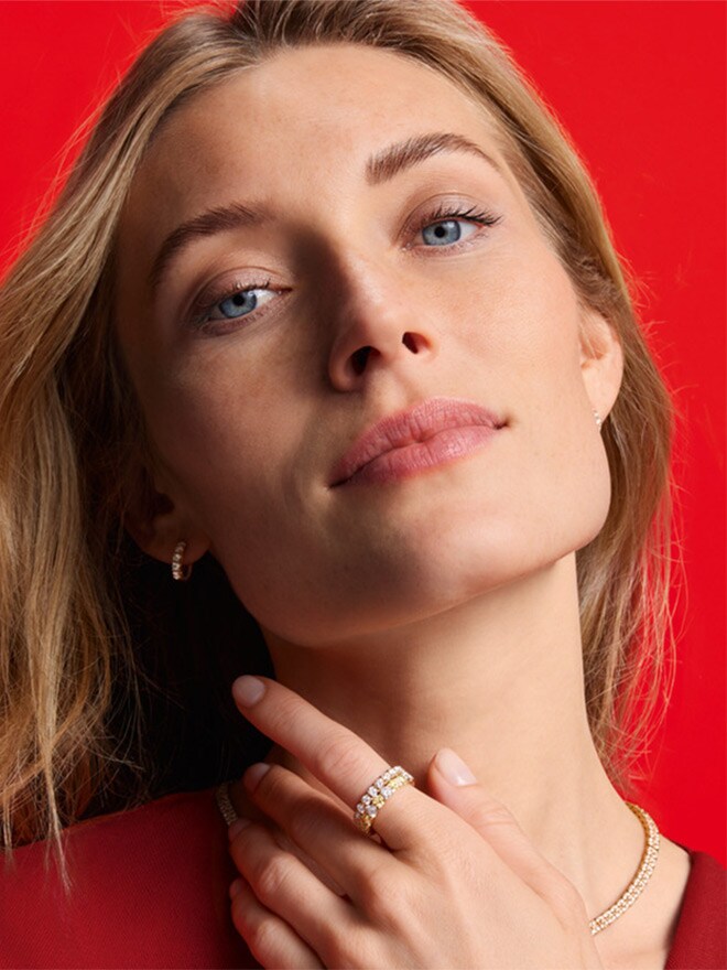 Blonde Frau trägt Memoire-Schmuck vor rotem Hintergrund