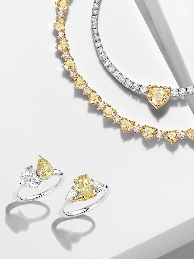 Two diamond necklaces and two rings from the Spotlight and Attraction lines with yellow diamonds on a white background